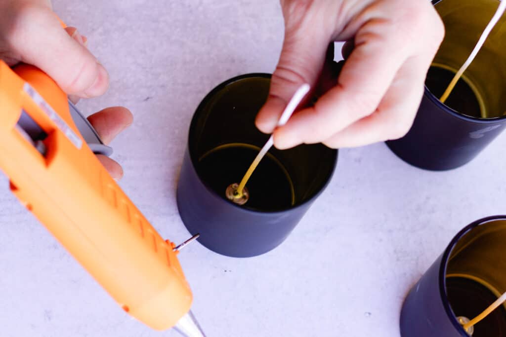 Glueing the wick to the bottom of the candle jar.