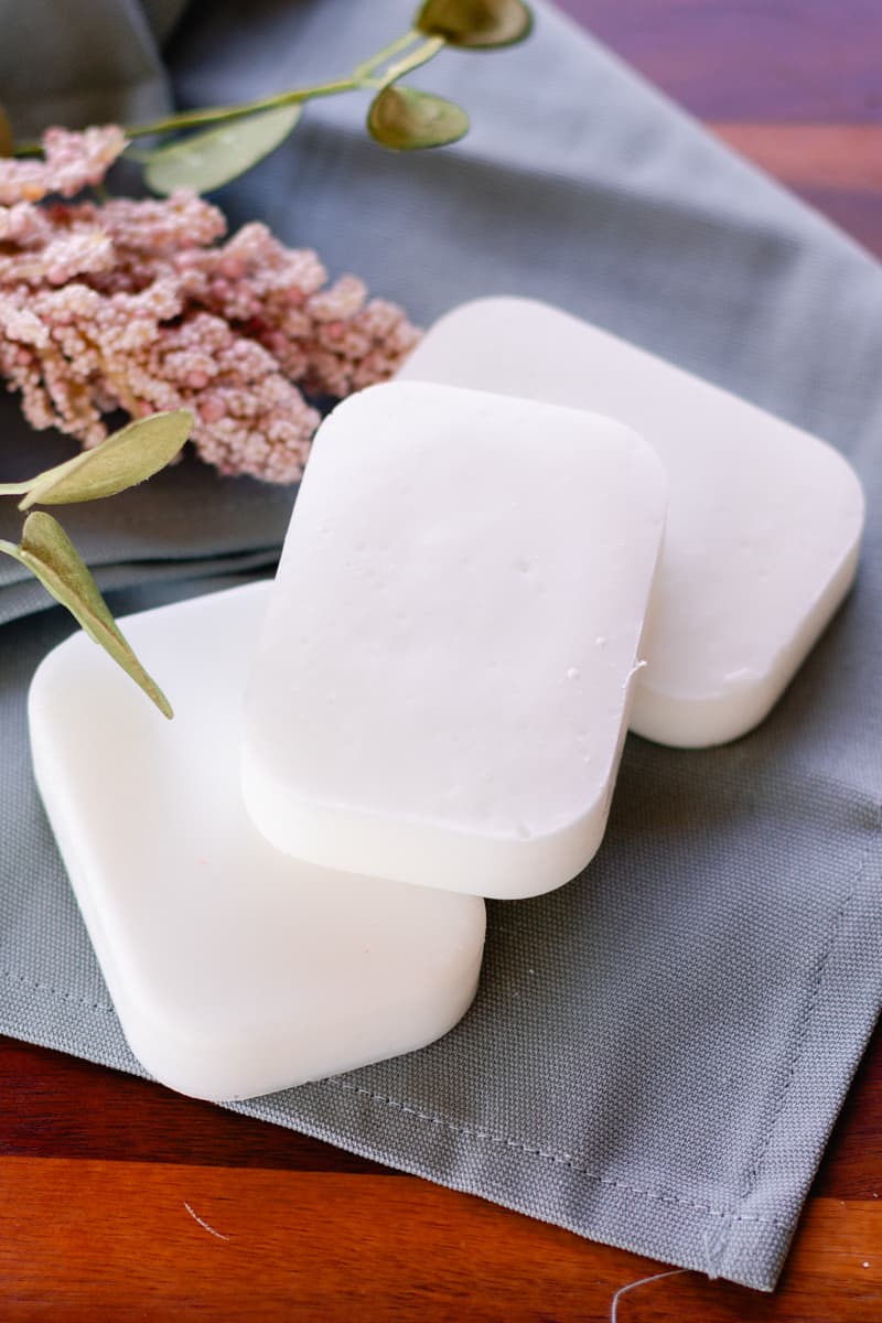 A stack of homemade coconut soap bars on a wooden tray.