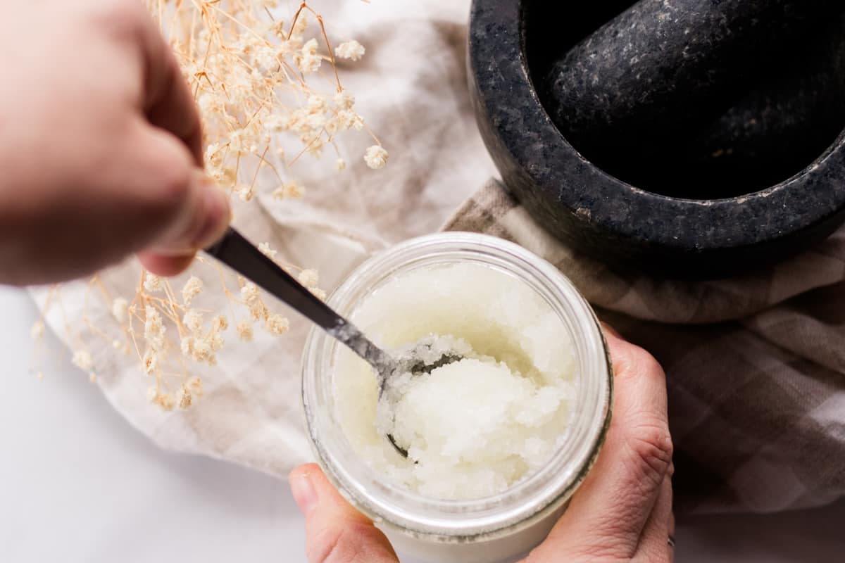 Using a spoon to stir the dead sea salt and oils together.