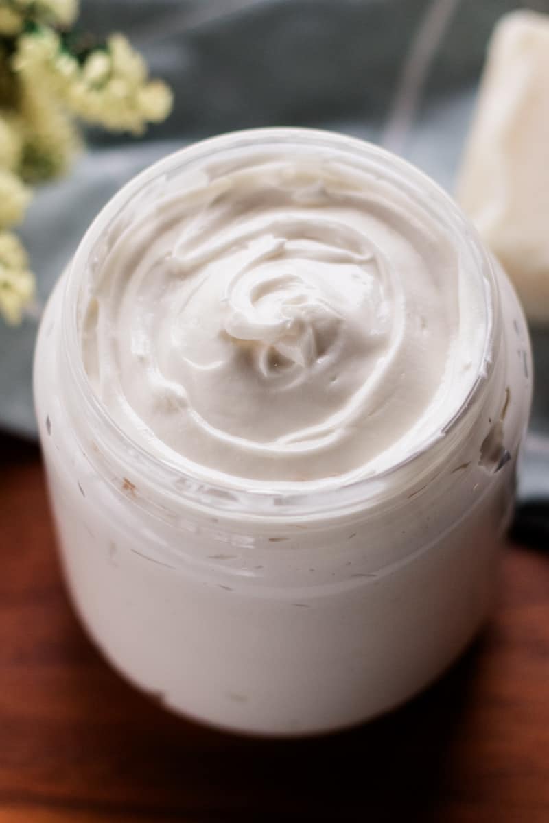 A beautiful hair butter recipe on a clear glass jar on a wooden table.