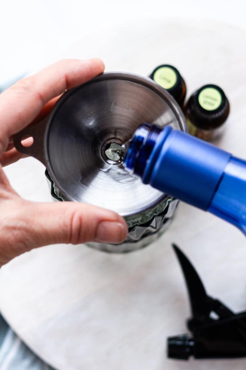 Pouring the vodka into the spray bottle to make the room spray.