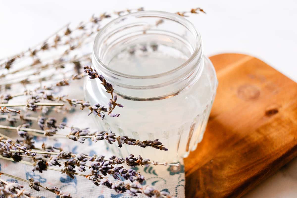 DIY hair gel with lavender springs on a wooden tray.
