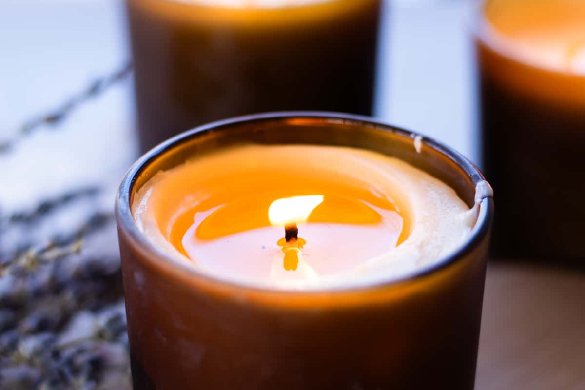 Flickering homemade massage candle in a amber colored candle jar.