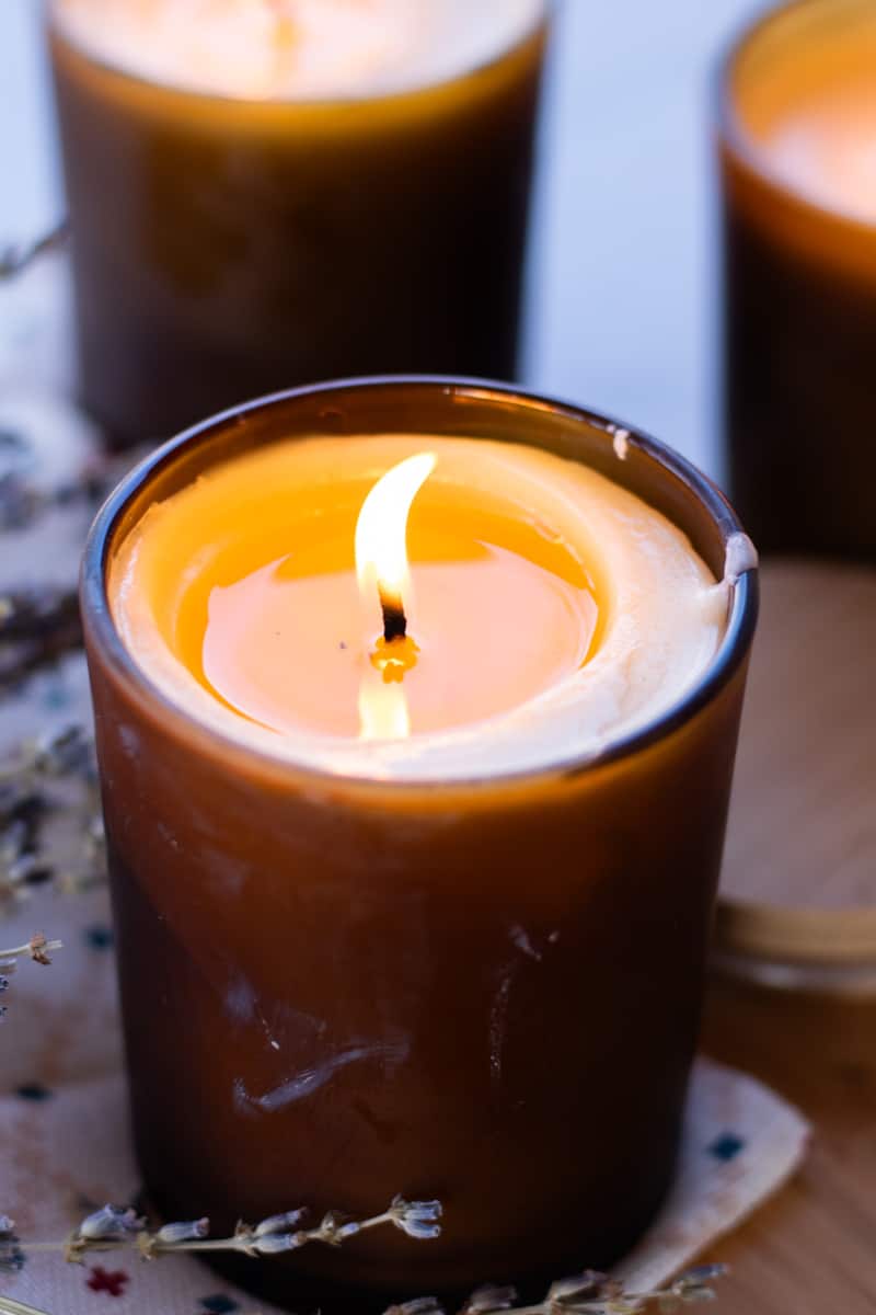A massage candle flickering in the dark on a night stand.