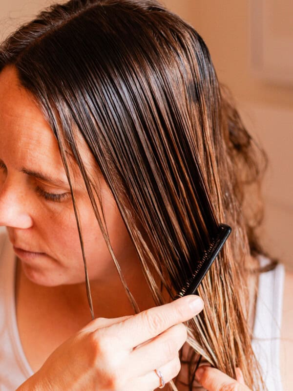 Combing hair oil into the strands of my hair so that its evenly distributed.