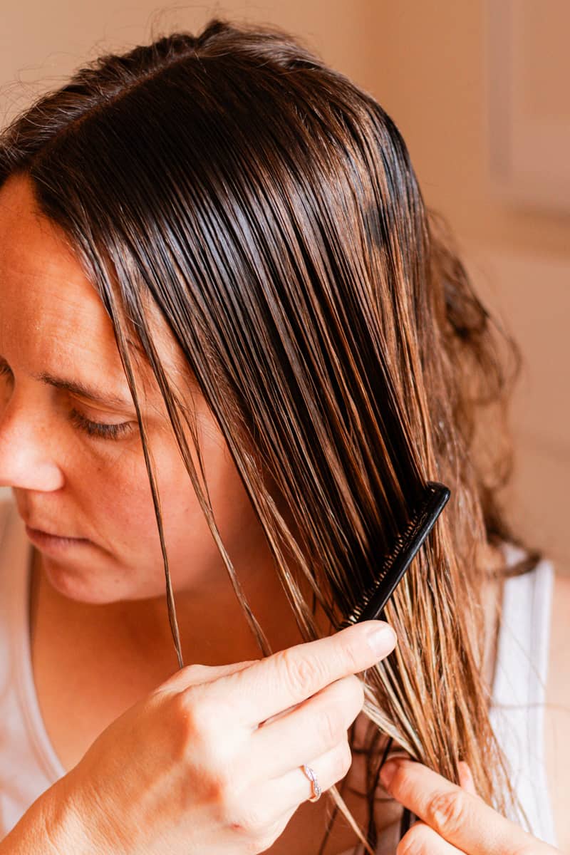 Using a comb to evenly distribute it throughout the hair.