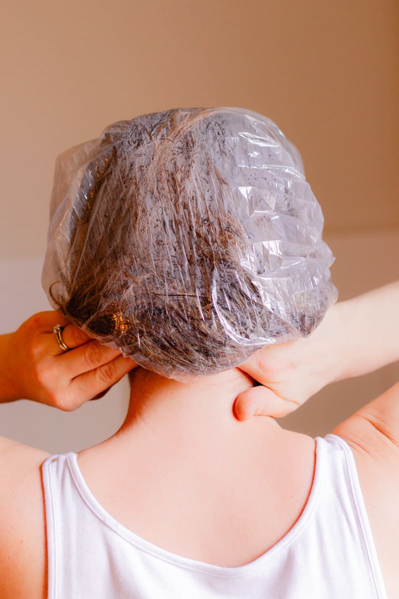 Putting on a shower cap to keep the hair mask from spreading.