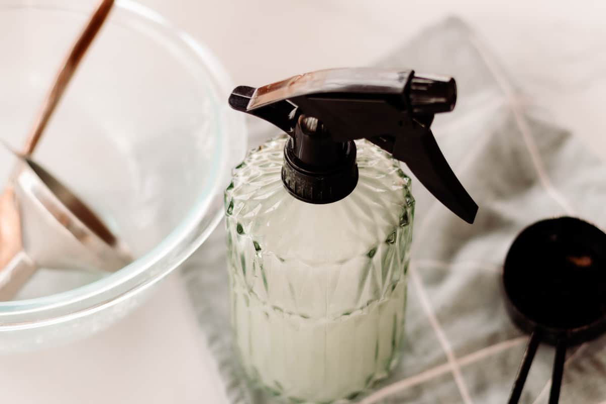 A glass spray bottle on a green and white towel.