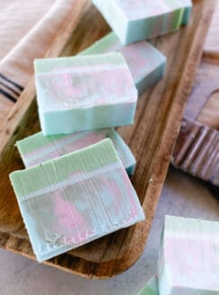 Marbled swirl coconut oil soap bars made with a melt and pour soap base on a wooden tray for drying.