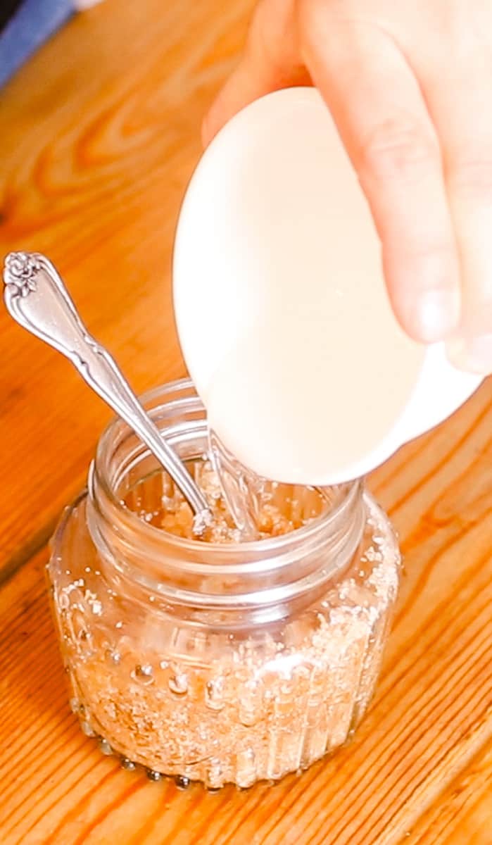Pouring the melted coconut oil over top the exfoliants. 