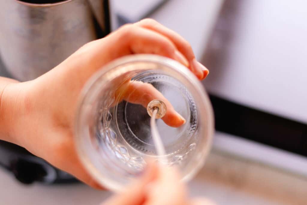 Glueing a candle wick to the bottom of a mason jar.