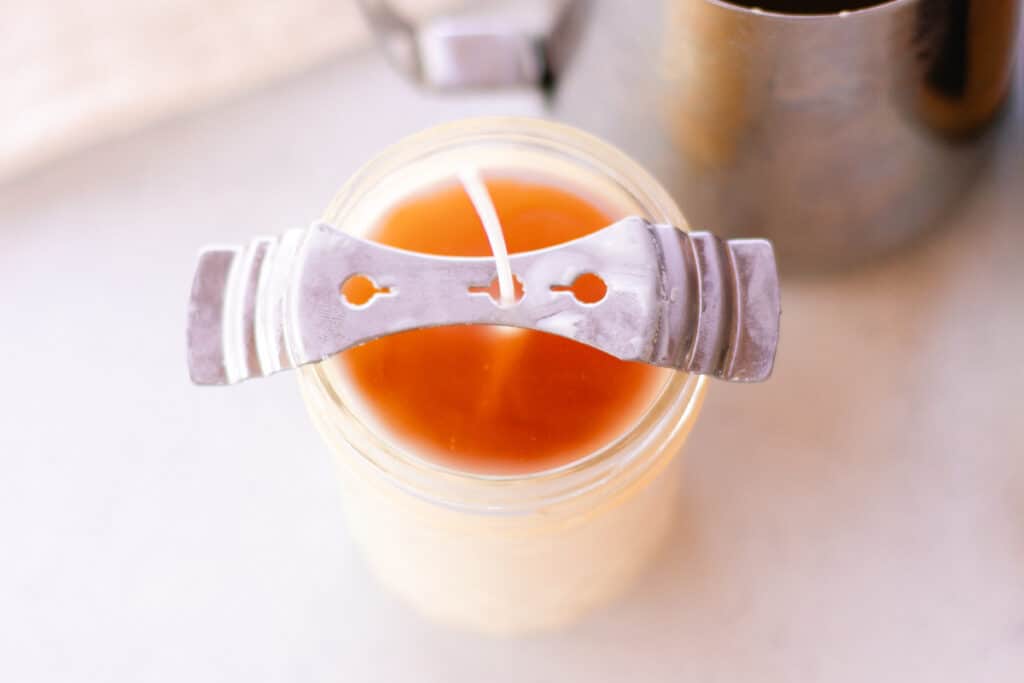 Centering the wick on the honey vanilla candles using a wick centering tool.