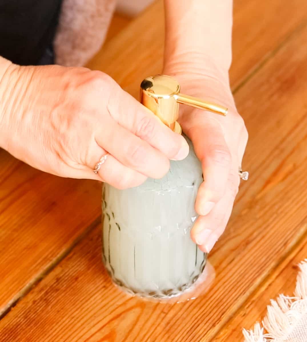 Securing the lid on a glass hand soap dispenser filled with homemade DIY liquid hand soap.