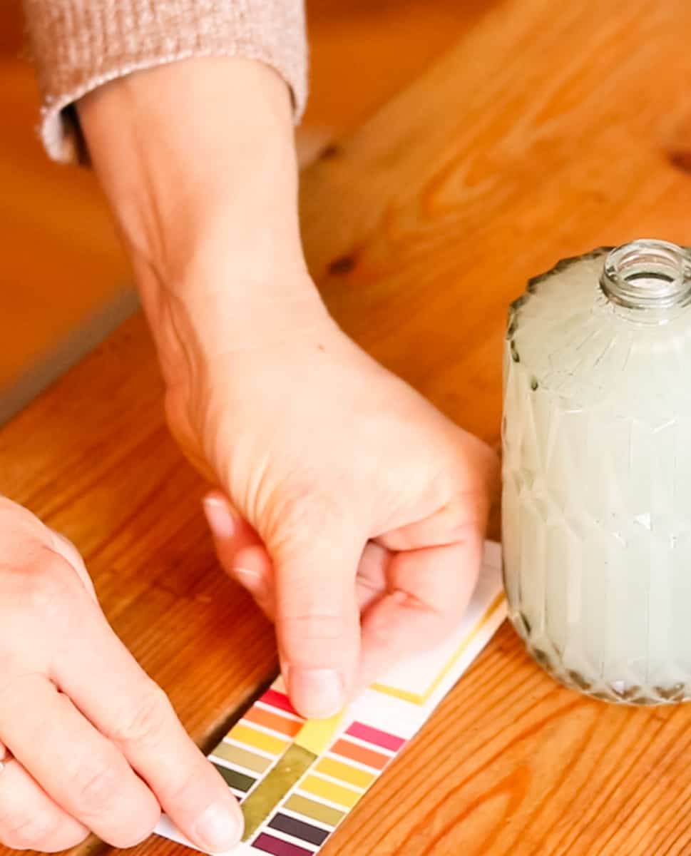 Using PH testing strips to test the PH level of homemade DIY liquid hand soap in a glass soap dispenser.