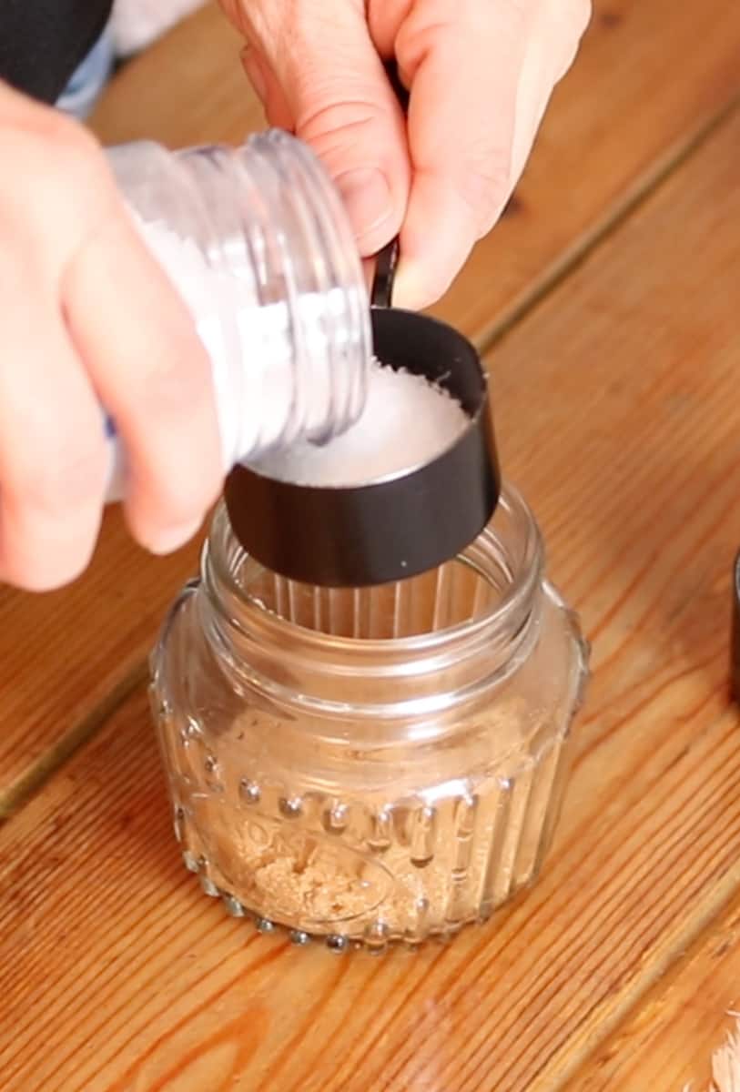 Measuring salt and adding it to the jar.