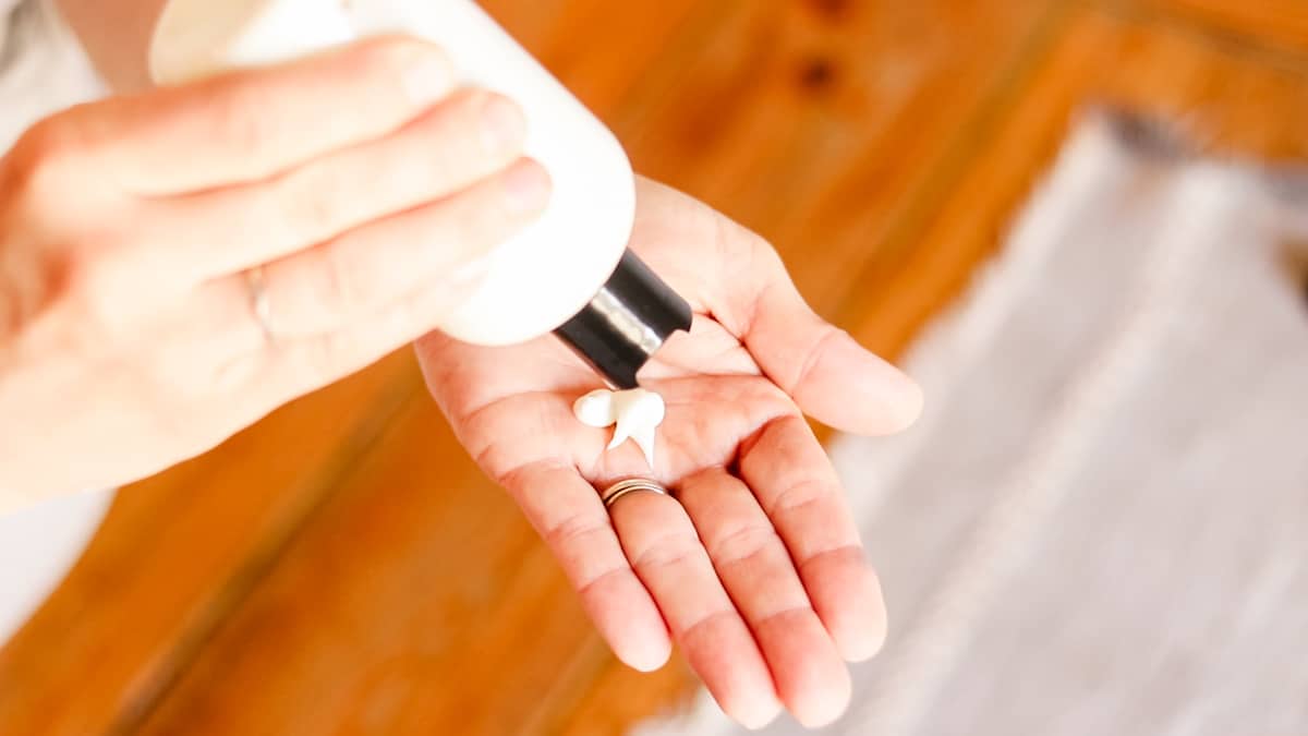Squeezing the homemade foot lotion into my hands before applying it to my feet.