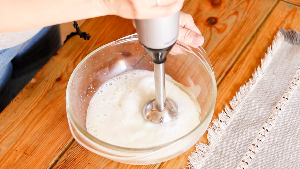 Mixing the lotion with an immersion blender to create an emulsion. 