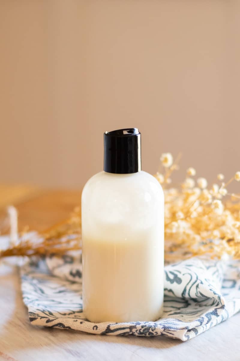 Squeeze top foot lotion with soothing ingredients on a wooden table with dried flowers in the background. 