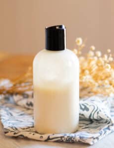 A homemade foot lotion in a plastic squeeze bottle sitting on a wooden table.
