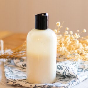 A DIY Foot lotion in a plastic squeeze bottle on a blue and white tea towel.