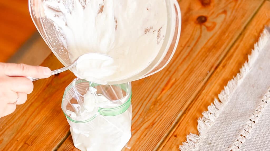 Scraping the lotion after it has cooled into a zippered bag.