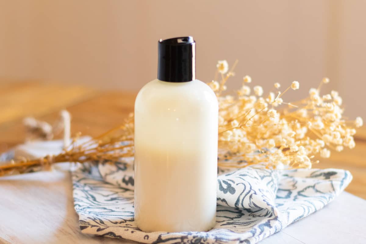 A DIY Foot lotion in a plastic squeeze bottle on a blue and white tea towel.