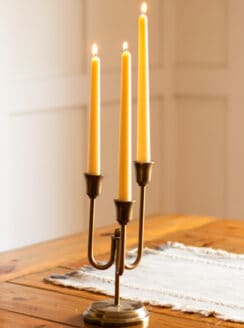 Taper beeswax candles burning brightly on a wooden table.