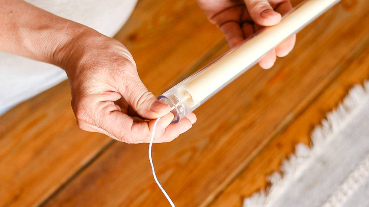 Tugging gently on the candle wick to remove the hardened candle from the taper mold.