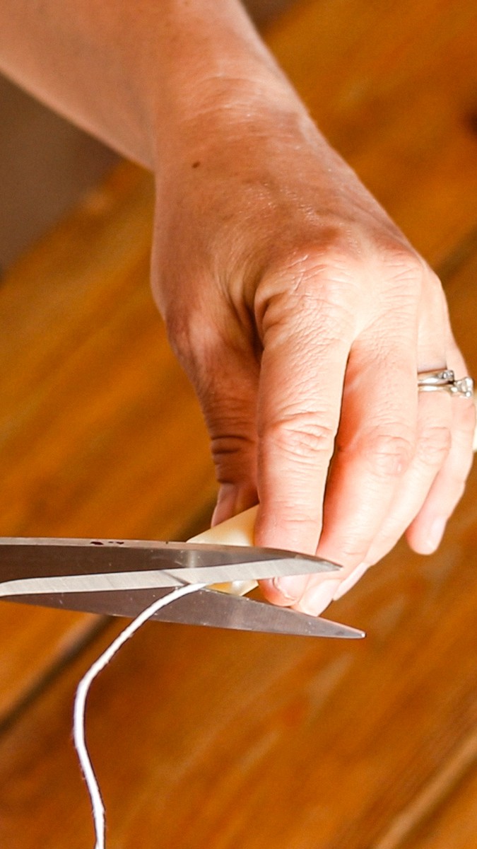 Trimming the end of the candle wick with scissors.