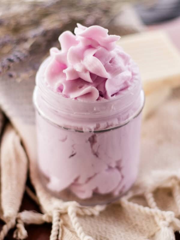 A homemade whipped soap with a fancy top sitting on a decorative tea towel.