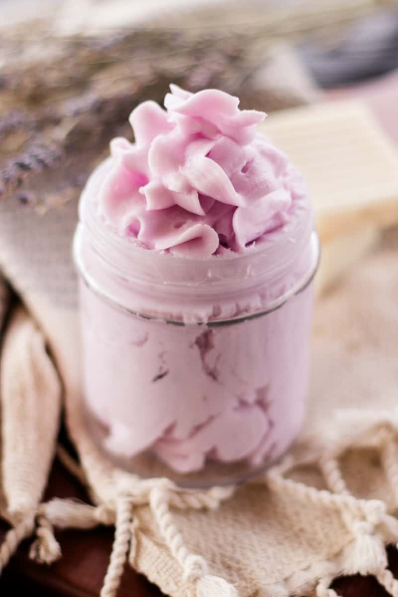 A homemade whipped soap with a fancy top sitting on a decorative tea towel.