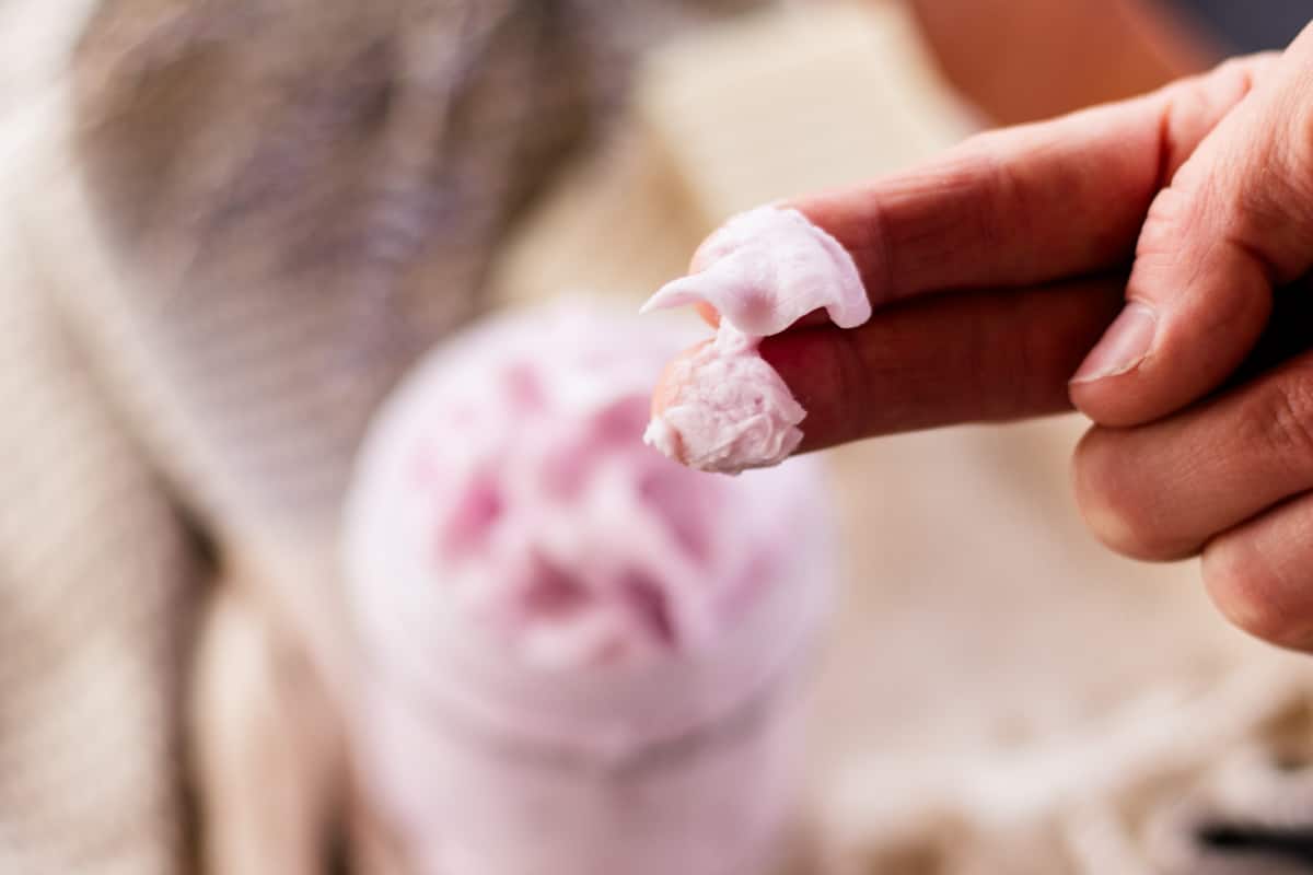 Two fingers dipping into the whipped soap recipe.