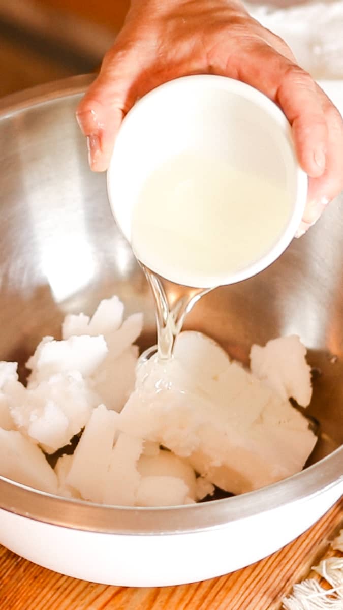 Adding the whipped soap base and a little bit of sweet almond oil to a mixing bowl.