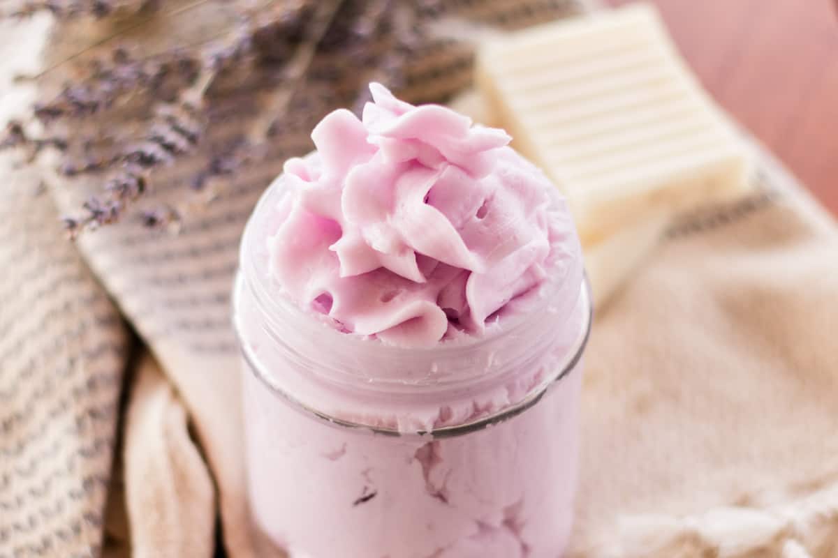 Fancy top soap with purple dye in a glass bowl with soap bars behind it.