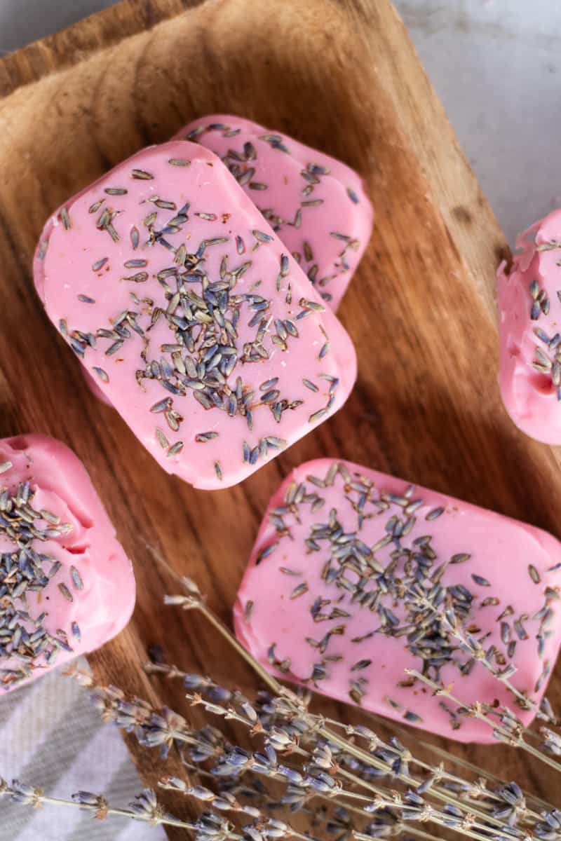 Bars of pink soap stacked on top of each other with lavender petals pressed into the surface of the bars.