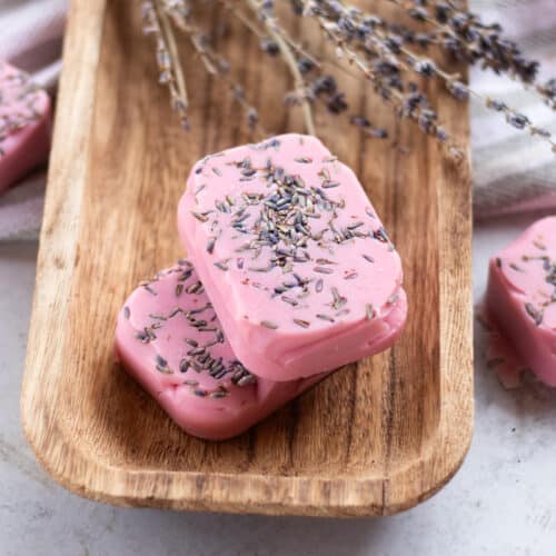 Homemade lavender soap bars with dried lavender buds curing on a wooden drying rack.
