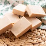 A pile of cold process soap bars on a wicker mat.