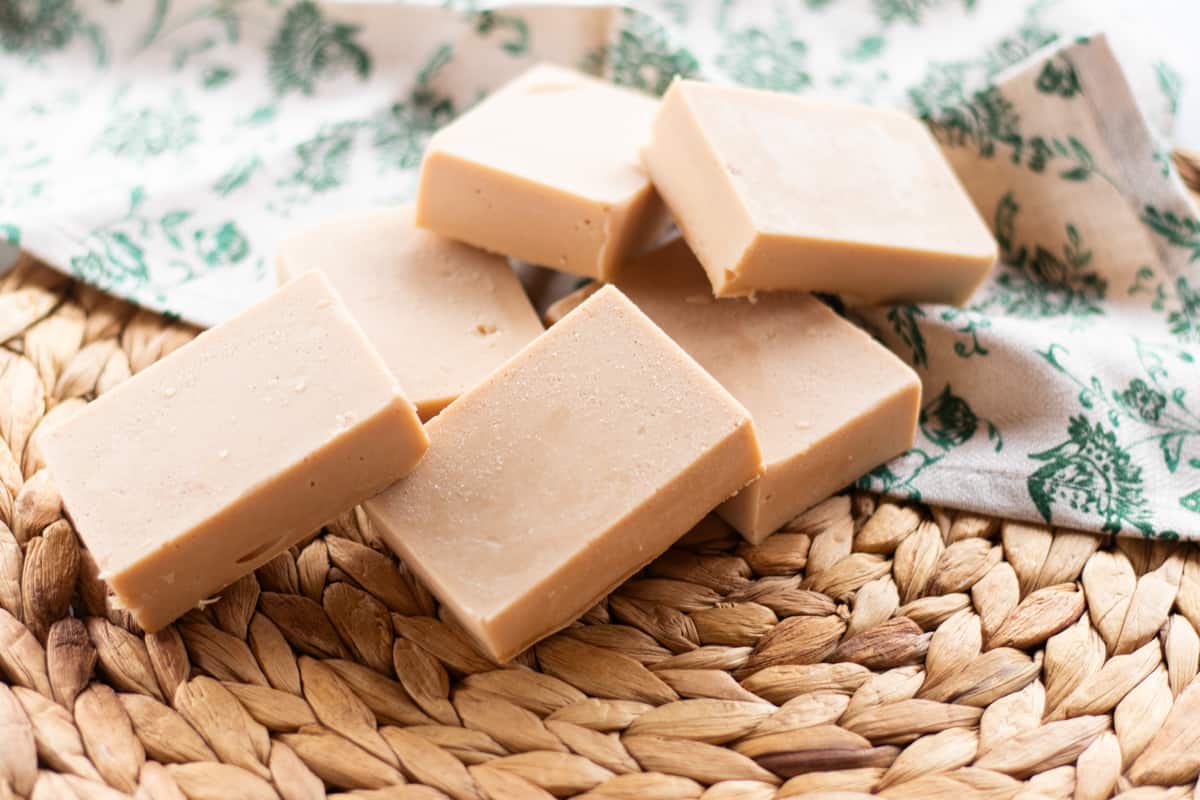 Six tan bars of cold-process soap on a piece of decorative material.