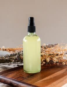 Whole body deodorant spray on a wooden tabletop with dried flowers in the background.