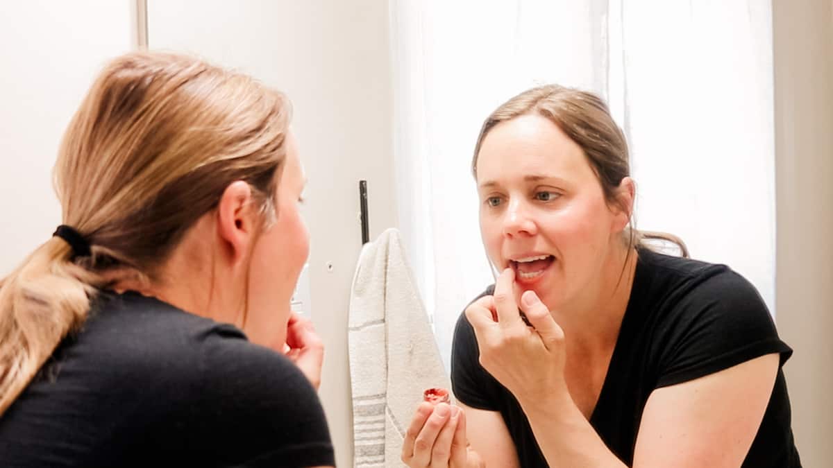 Applying tinted lip balm in a mirror.