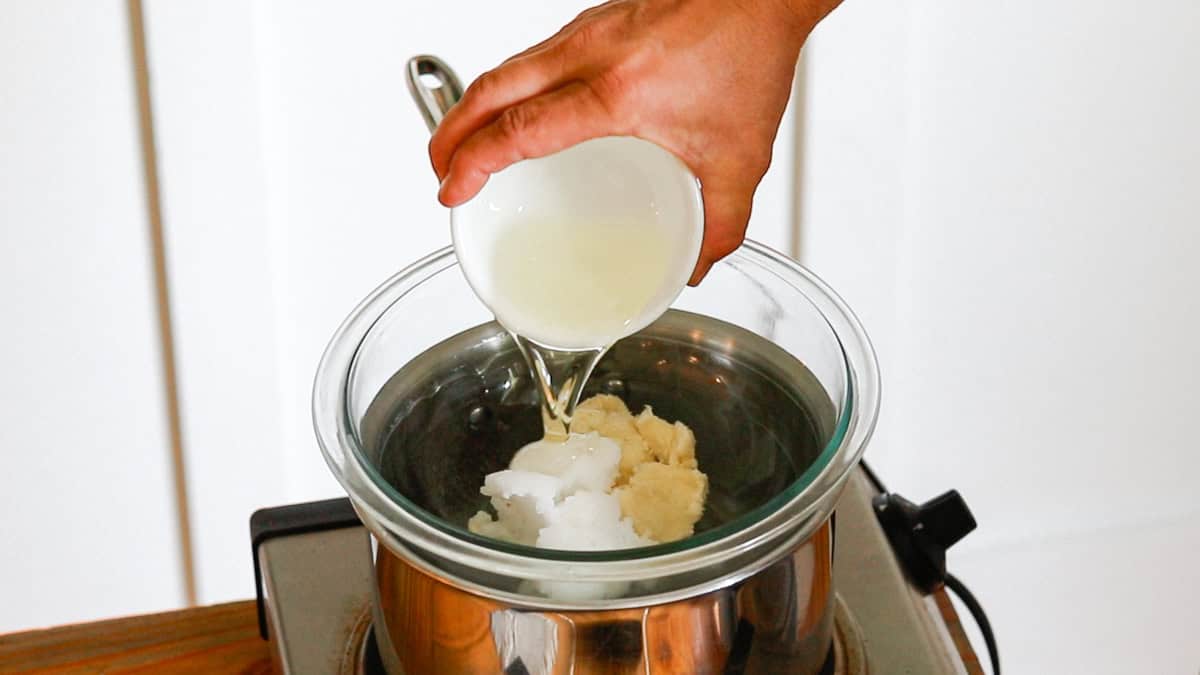 Pouring sunflower oil into a double boiler with the butters and coconut oil to make deodorant cream. 