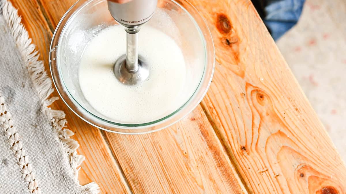 Using an immersion blender to mix the deodorant cream ingredients well. 
