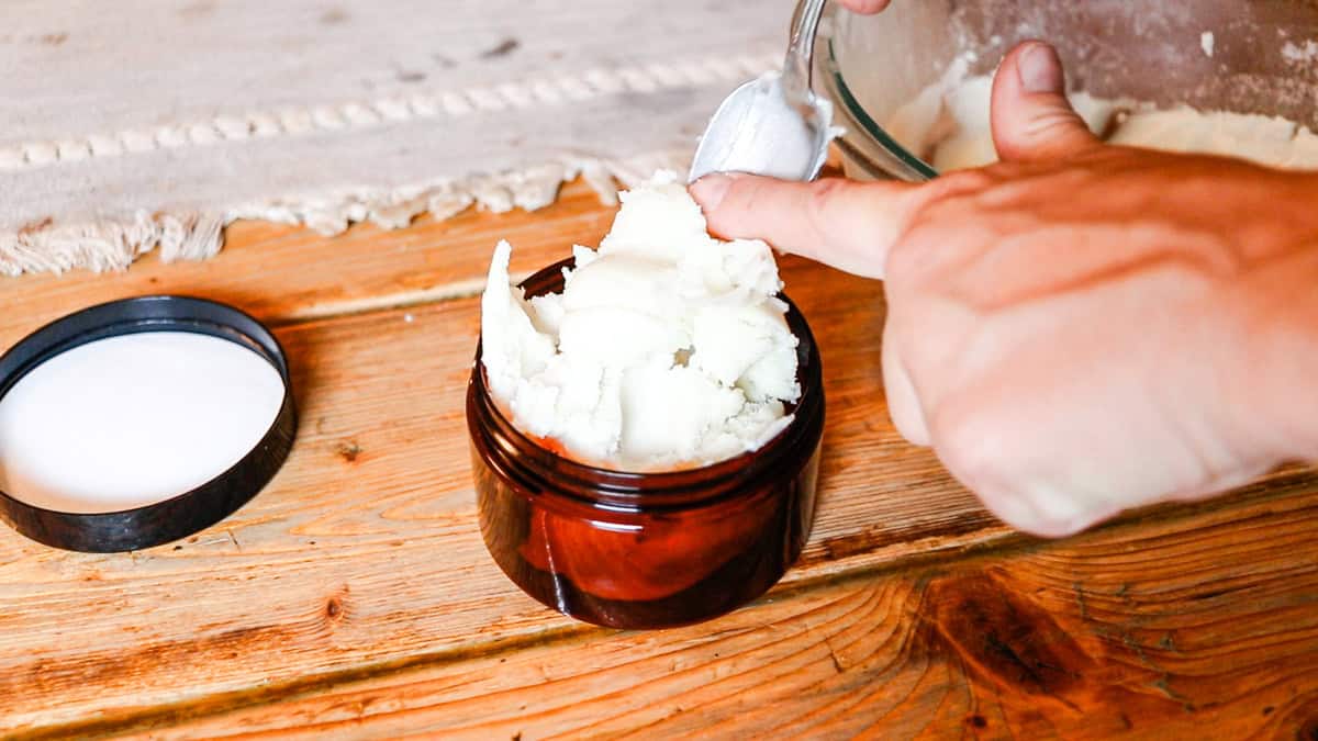Scooping the set deodorant cream into an amber container.
