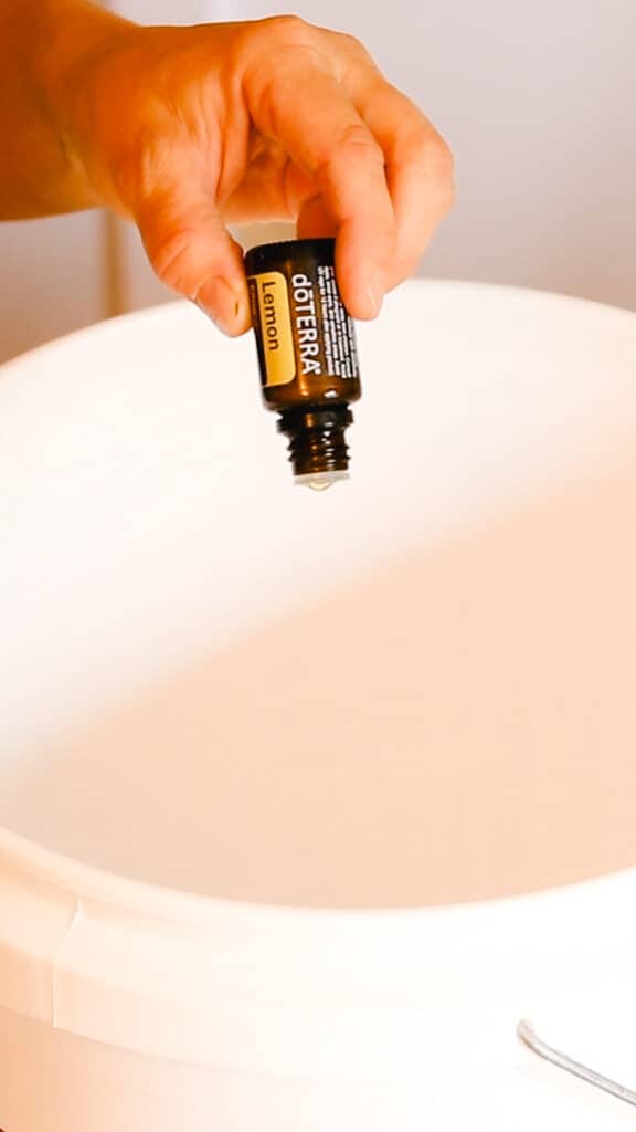 Adding lemon essential oil for fragrance to the 5 gallon bucket.