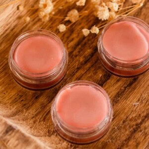 Three containers of tinted lip balm with the lids off.