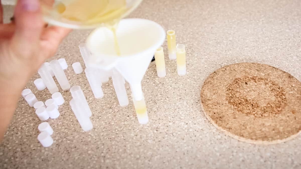 Pouring the melted lip balm into the empty tubes.