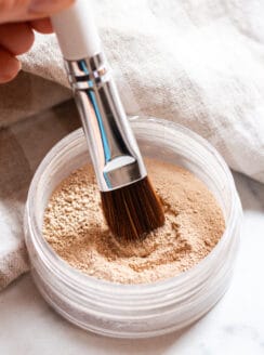 Dipping a makeup brush into the mineral makeup.