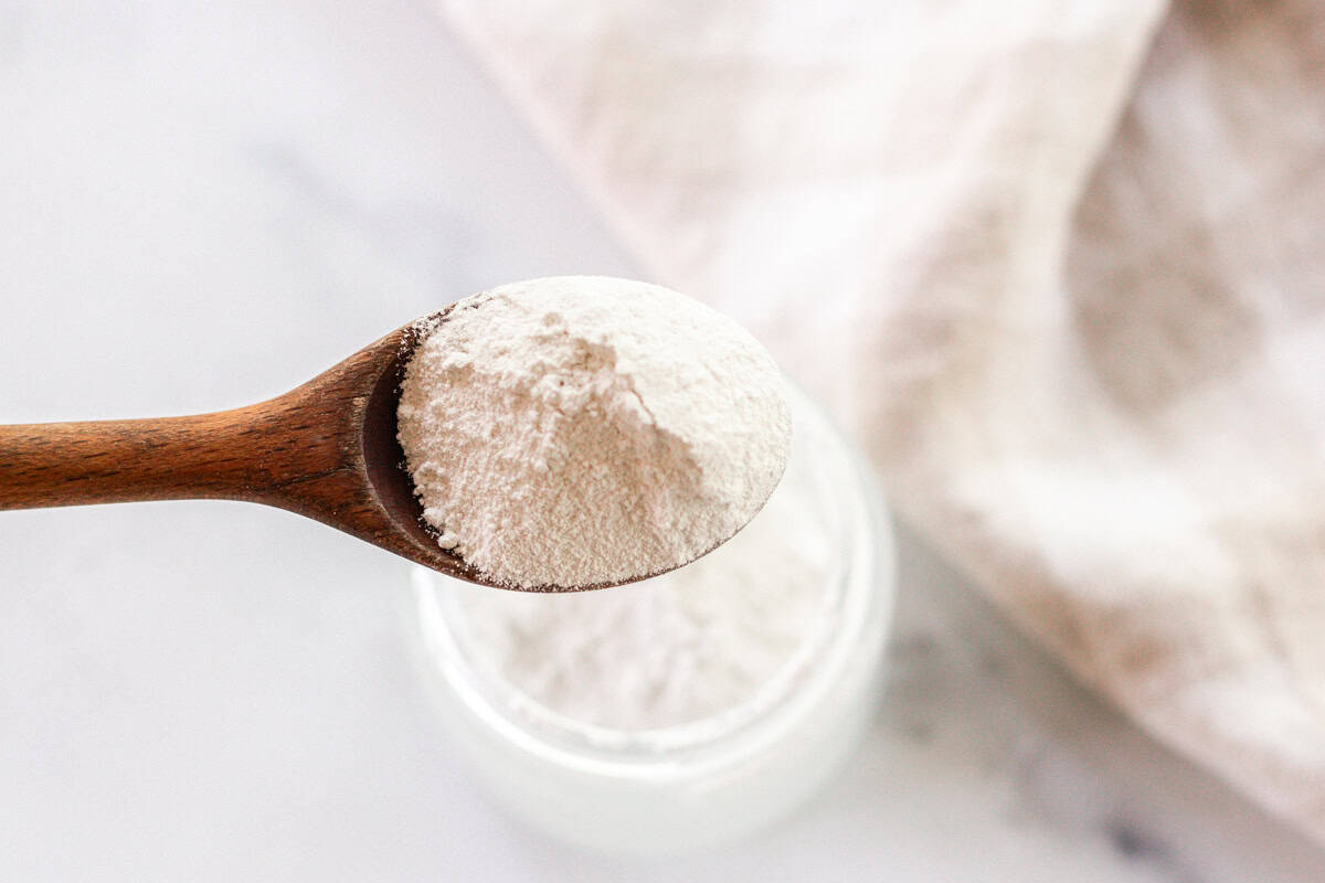 Using a spoon to add titanium dioxide and non-nano zinc oxide to a jar.