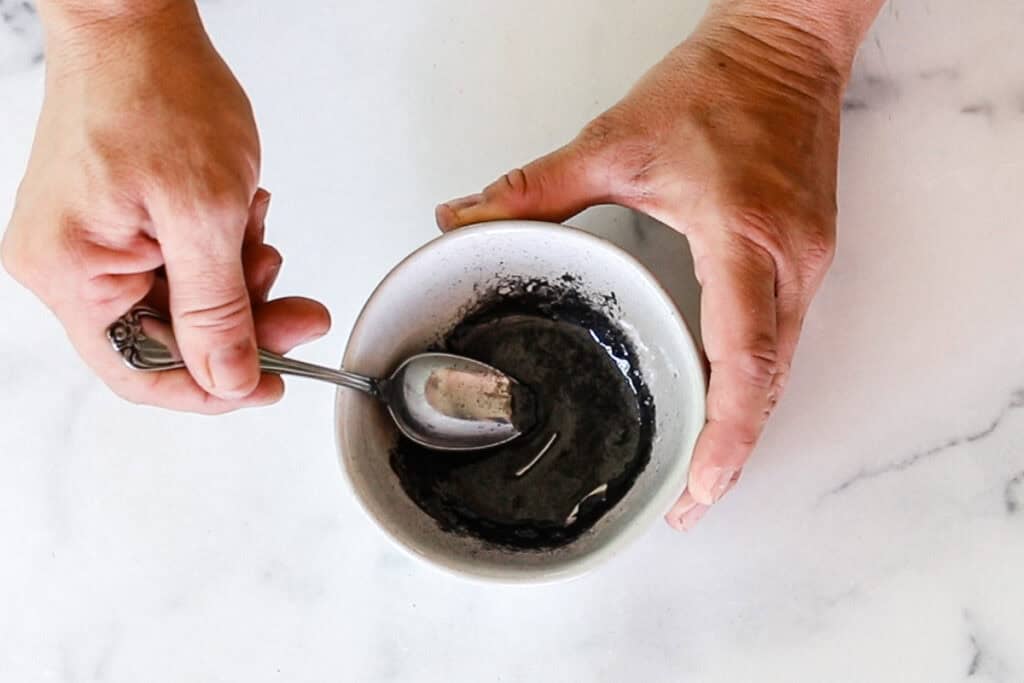 Adding in the mica powder to the melted ingredients and stirring it with a metal spoon. 