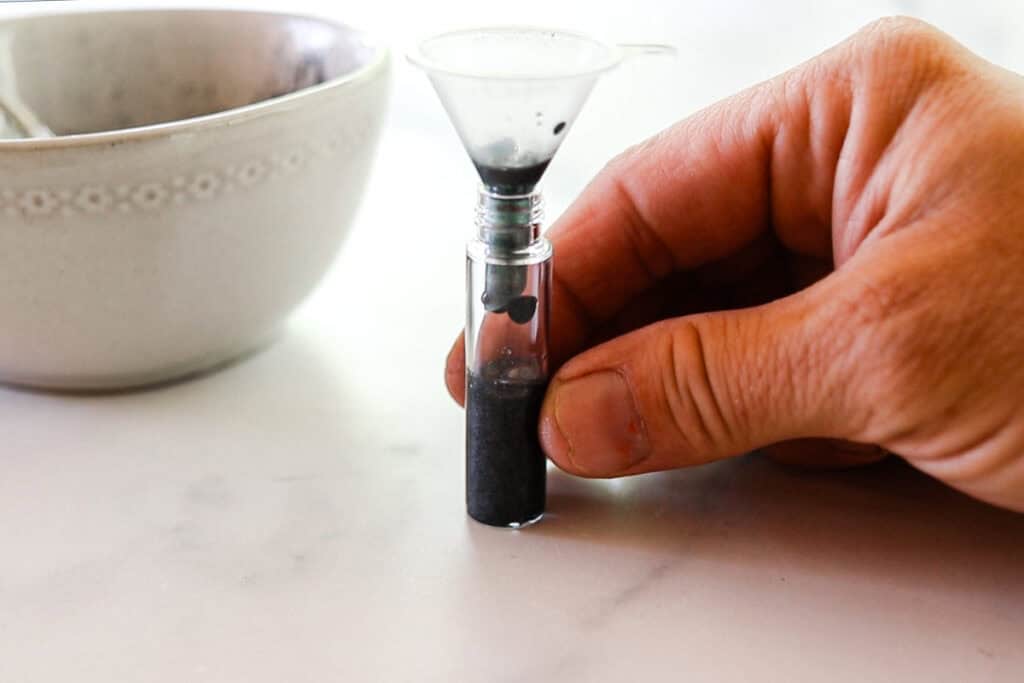 Transferring the homemade eyebrow gel from the bowl into the container for storage. I am using a small plastic funnel to prevent spills. 